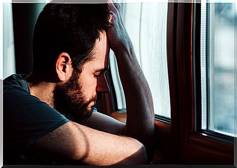 Anxious man leaning on the window symbolizing what to say to someone with anxiety