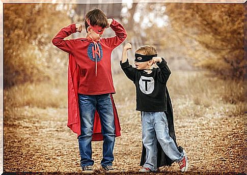 Older and little brother dressed as superheroes comparing each other