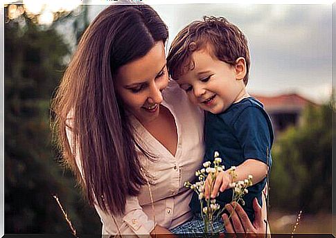 Mother with her son in her arms looking at a flower