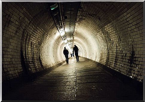 Two people walking in a tunnel