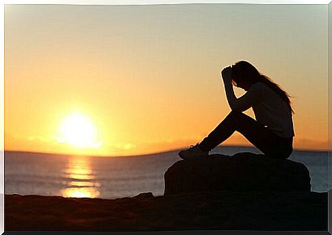 Woman showing her grief at sunset