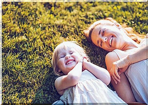 Mother and daughter lying on grass smiling