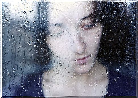 Sad woman behind a window wondering why disappointment hurts so much